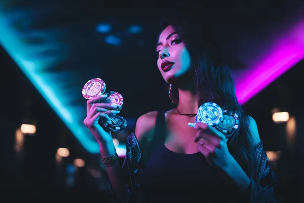 A young woman relaxing with her phone while dynamic casino elements float around her, illustrating the smooth mobile experience offered by the 47777 app.